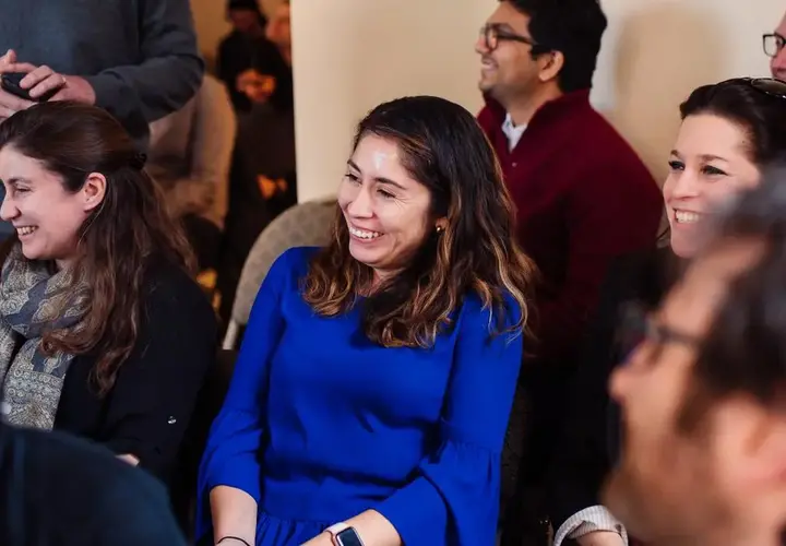 Presenters sitting and laughing in audience during conference. 